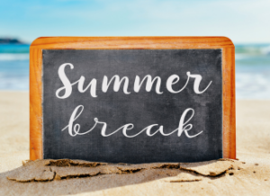 Chalkboard sign in the sand that says "Summer Break"