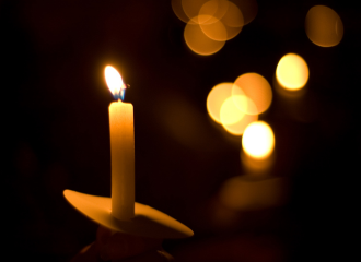 Lit candle among holiday lights.
