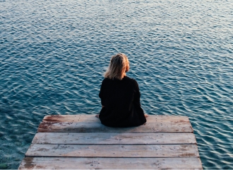 Women sitting on the edge of a dock looking out over the water, reflecting on recovery from binge eating disorder.